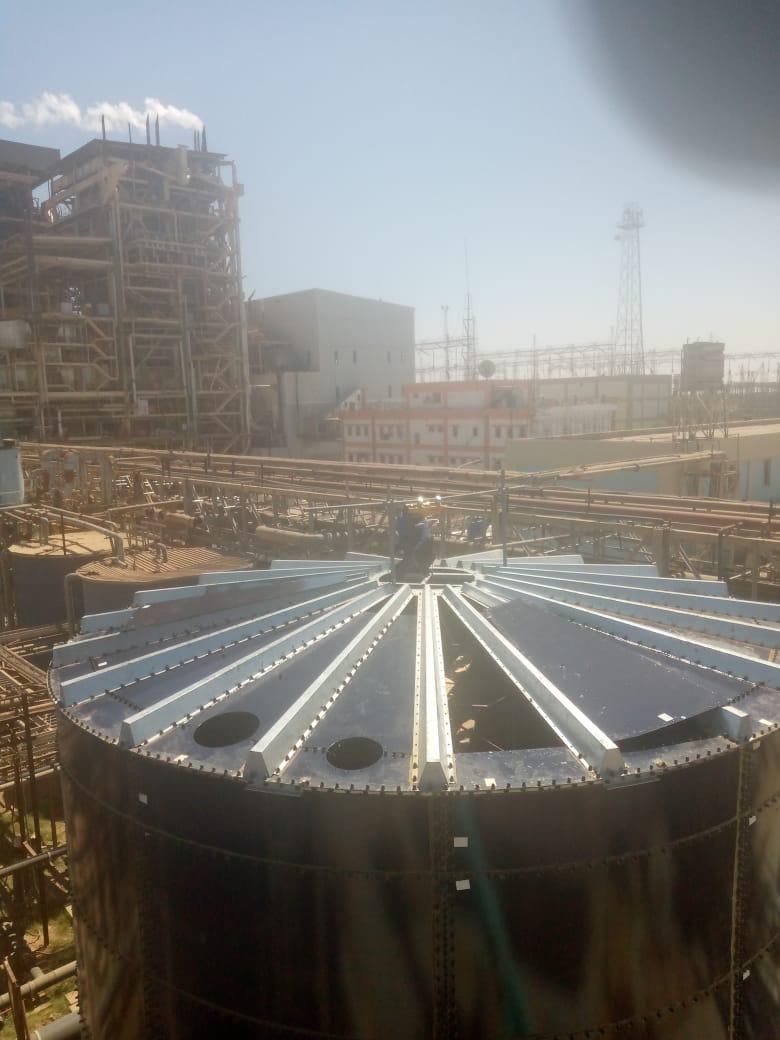 Radial roof rafters and deck panels being assembled on top of a bolted storage tank